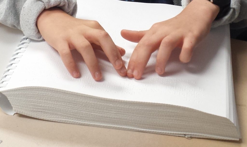 Photo of child's hands as they read braille
