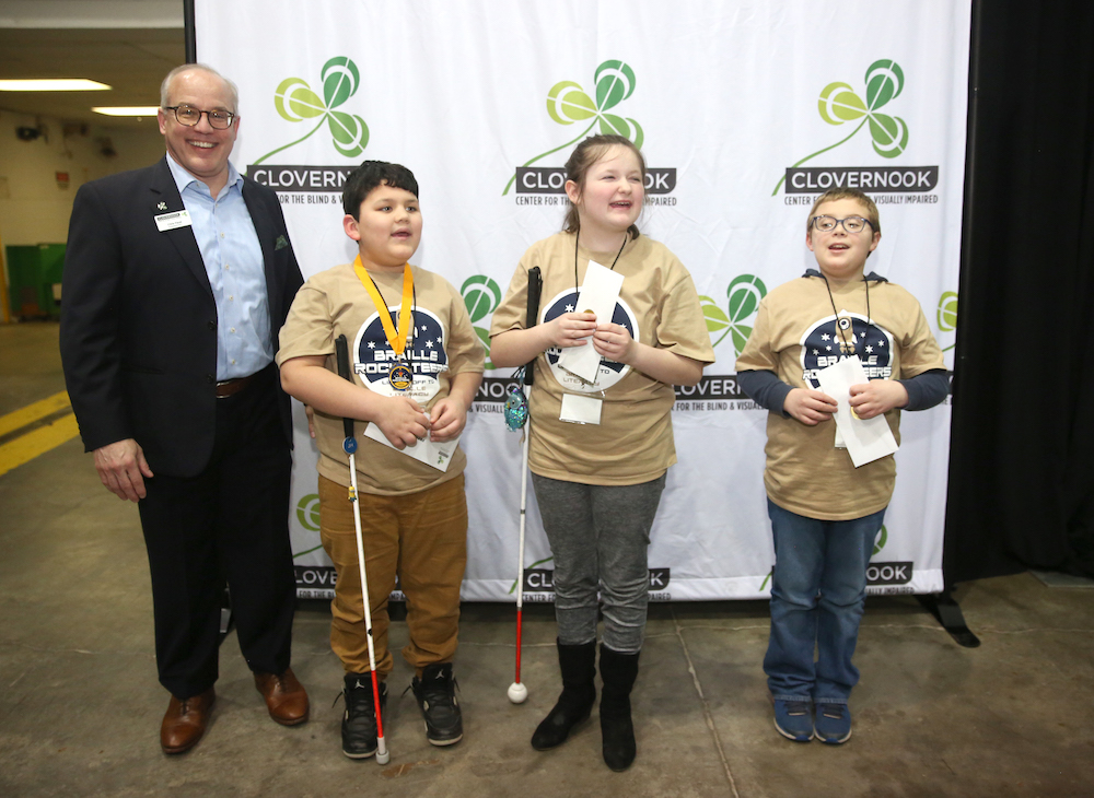 Three winners in the freshman category (grades 3 and 4) receive their prizes from Clovernook Center officials.