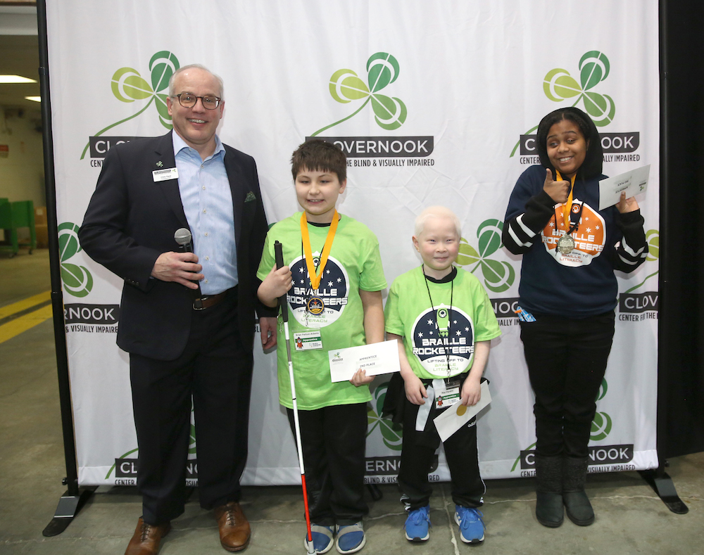 Three winners in the apprentice level (grades 1 and 2) receive their prizes from Clovernook Center officials.